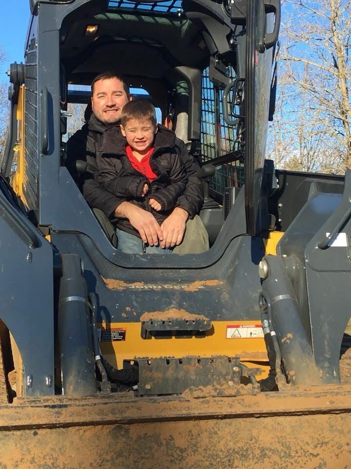 Josh Walker and his son together in the cab of a skid steer