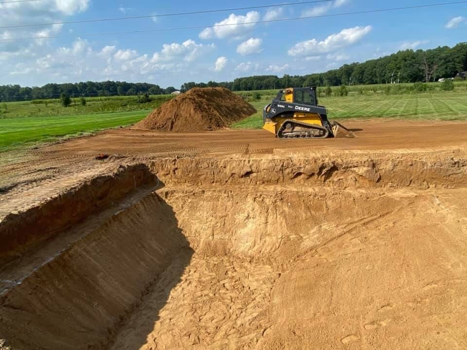 Skid steer cutting a deep excavation trench on a Michiana job site