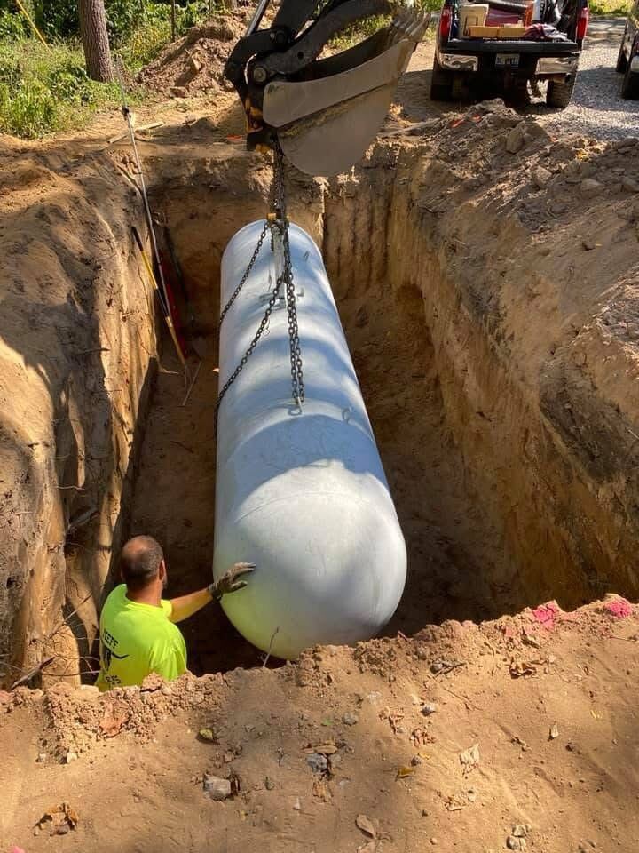 Septic tank being lowered into place with an excavator